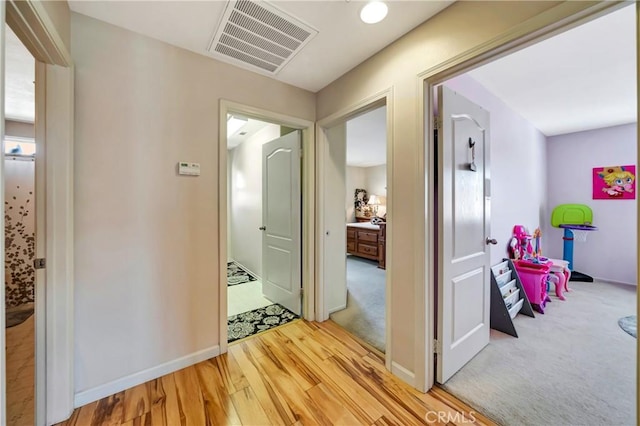 corridor featuring light wood-type flooring and baseboards