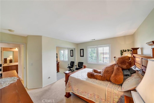 bedroom with light colored carpet, baseboards, a closet, and an office area