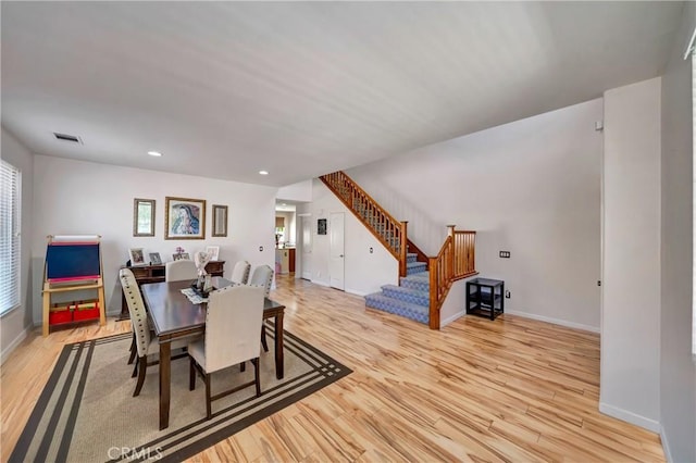 dining area with light wood finished floors, stairs, baseboards, and recessed lighting