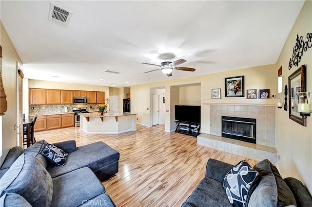 living area featuring a fireplace, light wood-style flooring, ceiling fan, baseboards, and recessed lighting
