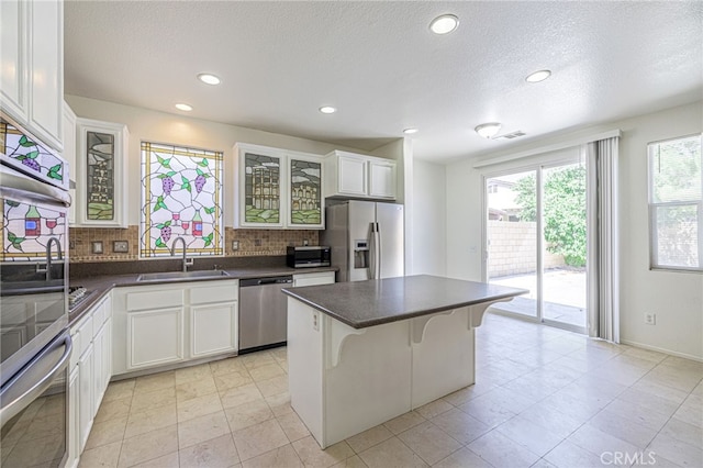 43839 58th St W, Lancaster, CA 93536 - kitchen with stainless steel appliances, a sink, backsplash, glass insert cabinets, and dark countertops