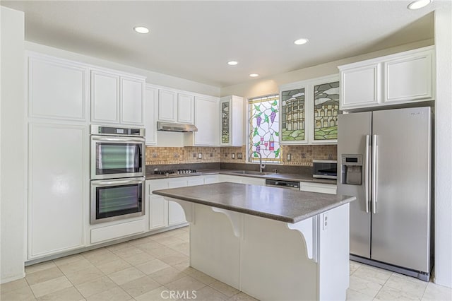 43839 58th St W, Lancaster, CA 93536 - kitchen featuring appliances with stainless steel finishes, a sink, dark countertops, a kitchen island, and white cabinetry