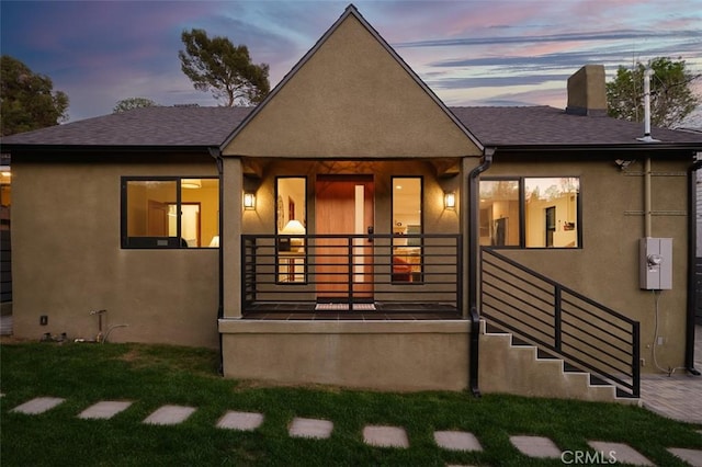 2136 Echo Park Ave, Los Angeles, CA 90026 - back of property at dusk with a chimney, stucco siding, roof with shingles, and a lawn