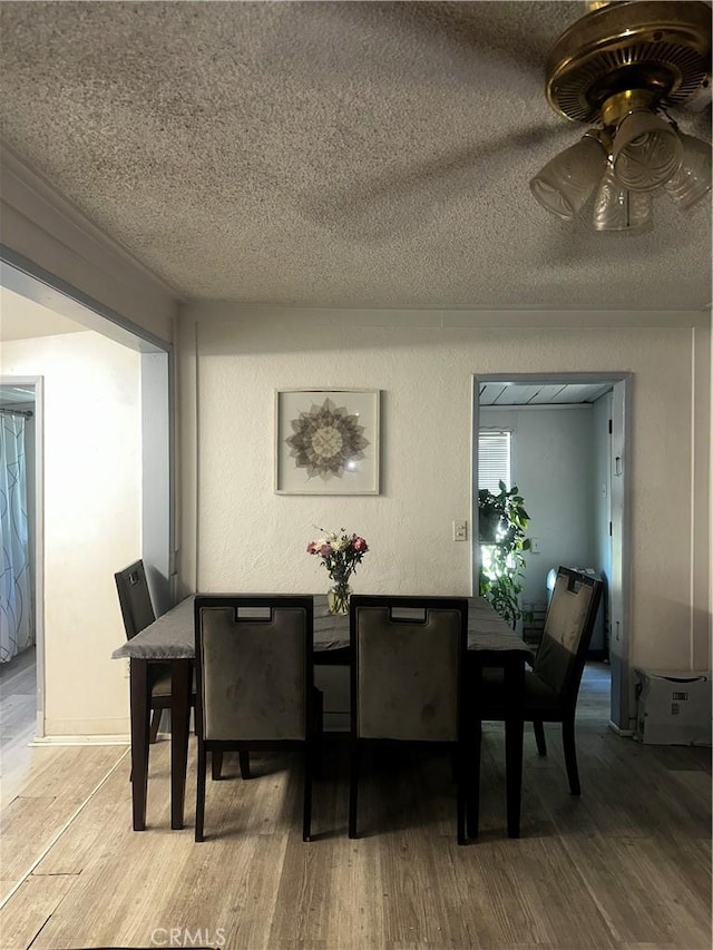 dining space with ceiling fan, wood finished floors, and a textured ceiling