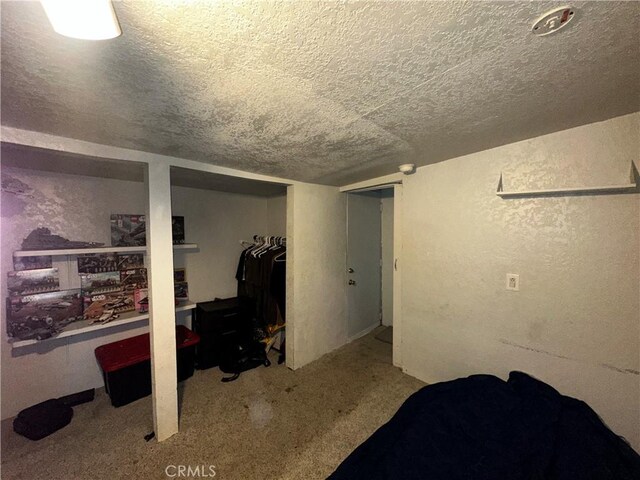 finished basement featuring a textured ceiling, a textured wall, and carpet floors
