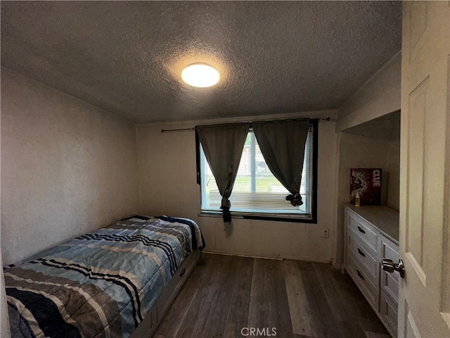 bedroom with a textured ceiling and dark wood-type flooring