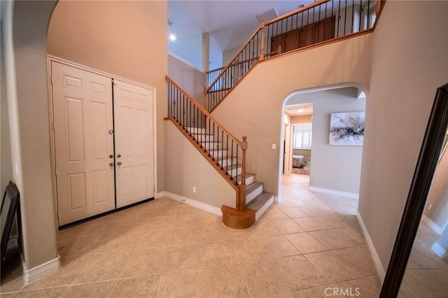 35197 Hogan Dr, Beaumont, CA 92223 - tiled entryway featuring arched walkways, a high ceiling, stairway, and baseboards
