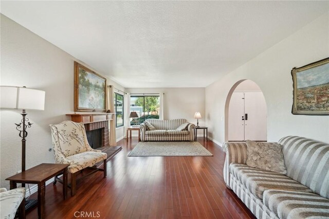 1824 S Starfire Ave, Corona, CA 92879 - living room with arched walkways, wood finished floors, baseboards, and a brick fireplace