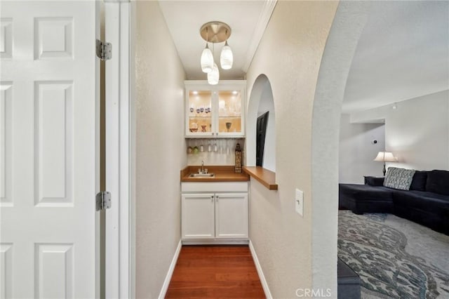 1824 S Starfire Ave, Corona, CA 92879 - indoor wet bar featuring dark wood-style flooring, baseboards, a textured wall, hanging light fixtures, and arched walkways