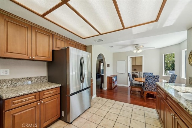 1824 S Starfire Ave, Corona, CA 92879 - kitchen featuring freestanding refrigerator, arched walkways, brown cabinetry, light tile patterned flooring, and a ceiling fan
