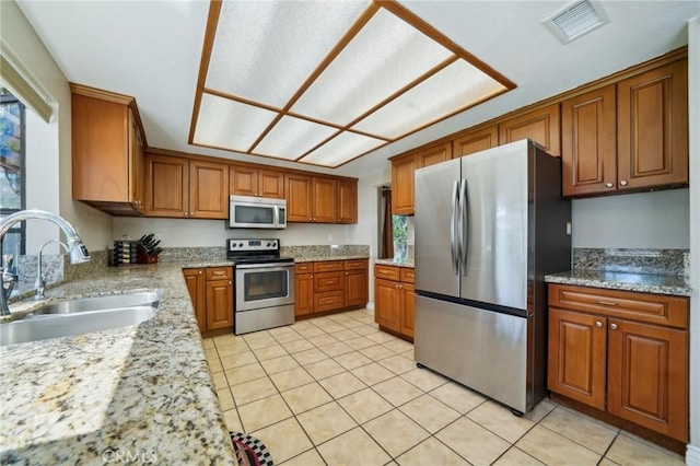1824 S Starfire Ave, Corona, CA 92879 - kitchen featuring stainless steel appliances, a sink, brown cabinets, light tile patterned floors, and light stone countertops