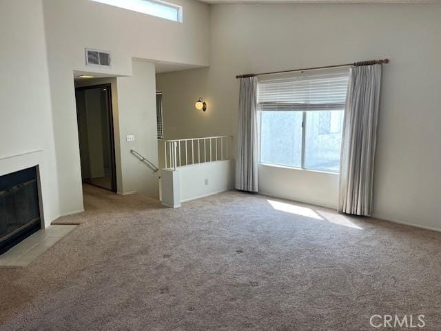 24222 Sylvan Glen Rd Unit F, Diamond Bar, CA 91765 - unfurnished living room with carpet flooring, plenty of natural light, a high ceiling, and a fireplace with flush hearth