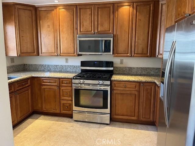 24222 Sylvan Glen Rd Unit F, Diamond Bar, CA 91765 - kitchen featuring appliances with stainless steel finishes, brown cabinets, and light stone counters