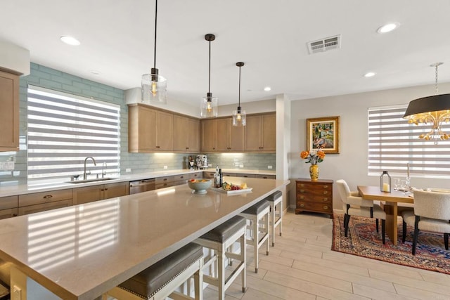 6132 Colt Pl Unit 101, Carlsbad, CA 92009 - kitchen featuring light countertops, backsplash, a breakfast bar area, stainless steel dishwasher, and light wood finished floors