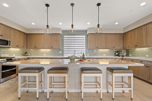6132 Colt Pl Unit 101, Carlsbad, CA 92009 - kitchen featuring stainless steel appliances, light countertops, backsplash, a center island, and a breakfast bar area