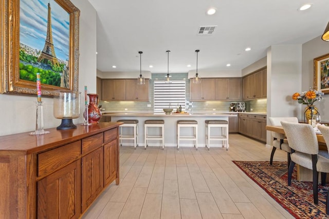 6132 Colt Pl Unit 101, Carlsbad, CA 92009 - kitchen featuring backsplash, a breakfast bar area, recessed lighting, light wood-style flooring, and light countertops