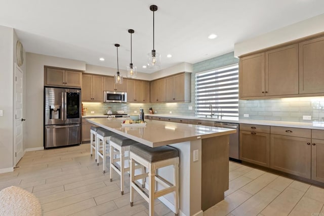 6132 Colt Pl Unit 101, Carlsbad, CA 92009 - kitchen featuring stainless steel appliances, a center island, a breakfast bar, backsplash, and light wood-style flooring
