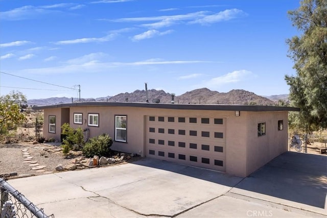 61961 Aster Pl, Joshua Tree, CA 92252 - view of front of property featuring a mountain view, stucco siding, concrete driveway, and an attached garage