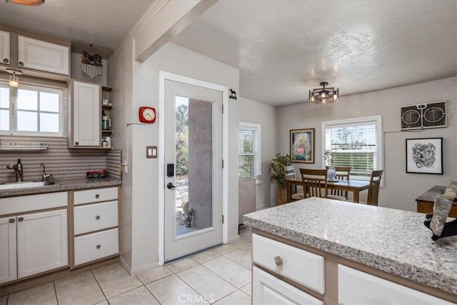 61961 Aster Pl, Joshua Tree, CA 92252 - kitchen featuring a sink, light tile patterned floors, decorative backsplash, white cabinets, and a textured ceiling