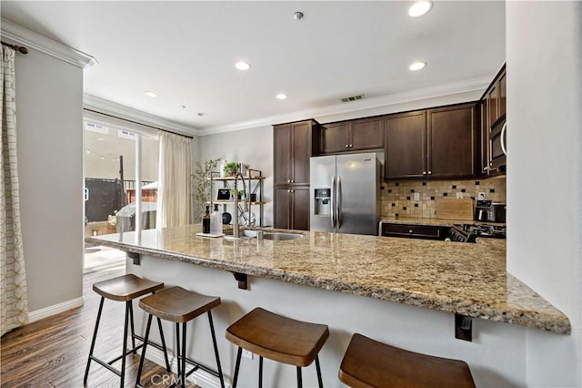 27423 Larabee Ct Unit 3, Murrieta, CA 92562 - kitchen with stainless steel appliances, dark brown cabinetry, light stone countertops, ornamental molding, and dark wood finished floors