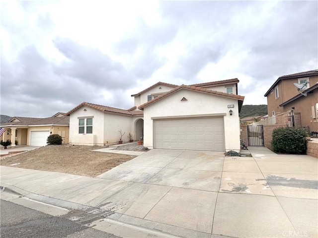 18016 Ribwort Rd, San Bernardino, CA 92407 - mediterranean / spanish home with stucco siding, concrete driveway, a garage, a gate, and a tiled roof