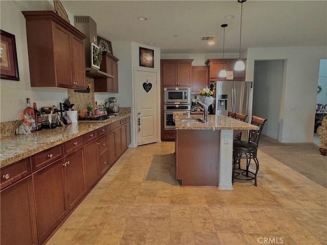 18016 Ribwort Rd, San Bernardino, CA 92407 - kitchen with appliances with stainless steel finishes, a sink, an island with sink, hanging light fixtures, and a kitchen bar