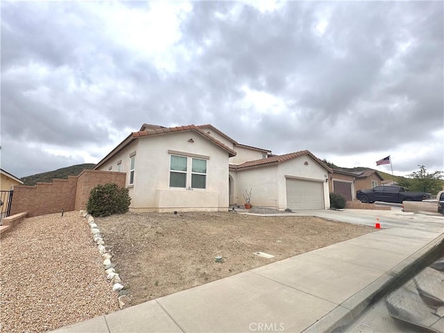18016 Ribwort Rd, San Bernardino, CA 92407 - mediterranean / spanish-style house with fence, stucco siding, a garage, and a tile roof