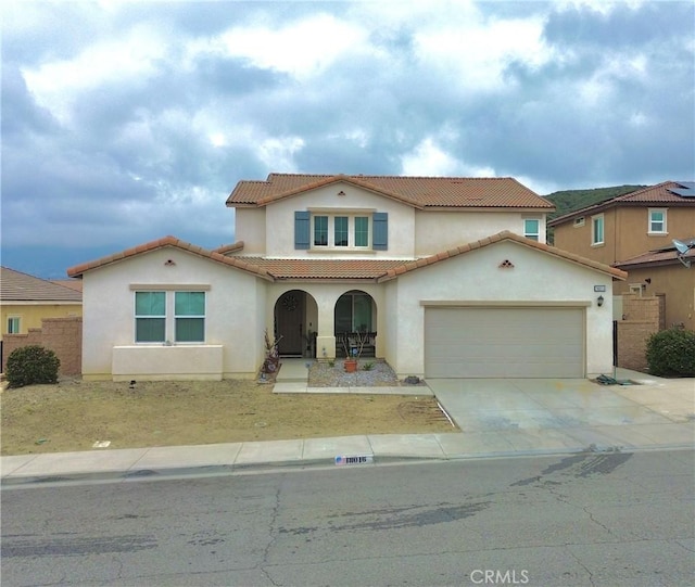 18016 Ribwort Rd, San Bernardino, CA 92407 - mediterranean / spanish-style house with stucco siding, a tiled roof, driveway, a garage, and covered porch