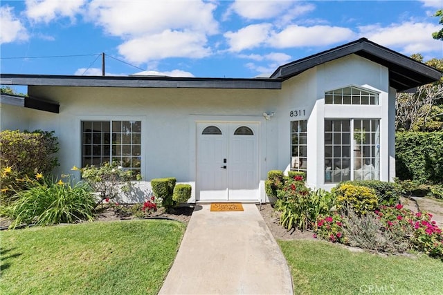 entrance to property with stucco siding and a lawn