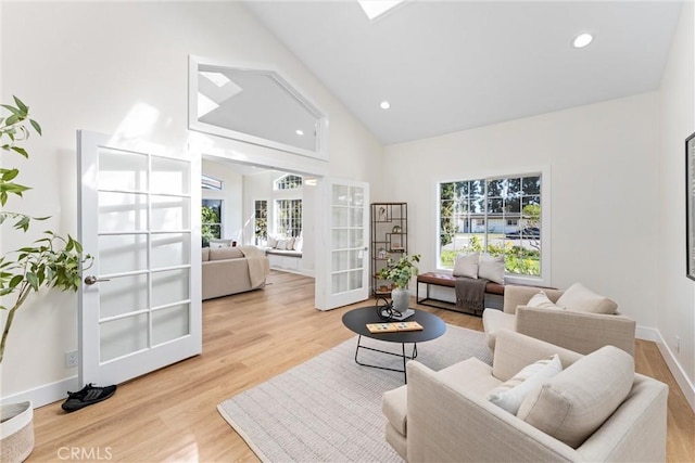 living area with french doors, plenty of natural light, wood finished floors, recessed lighting, and high vaulted ceiling
