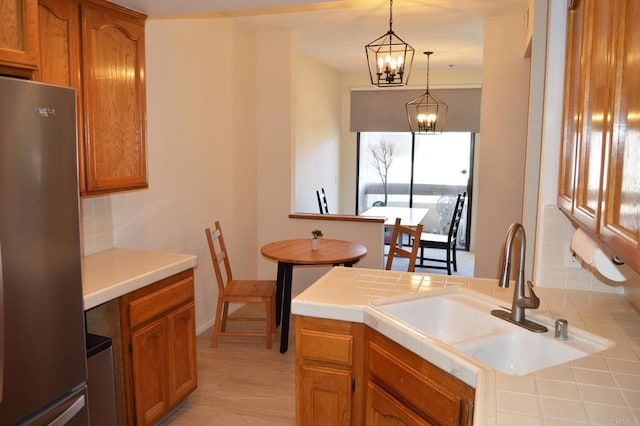 5845 Friars Rd Unit 1316, San Diego, CA 92110 - kitchen with freestanding refrigerator, a sink, tile countertops, and brown cabinets