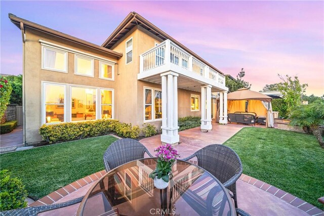 22541 Wakefield, Mission Viejo, CA 92692 - back of house at dusk featuring a balcony, a hot tub, a patio area, and a yard
