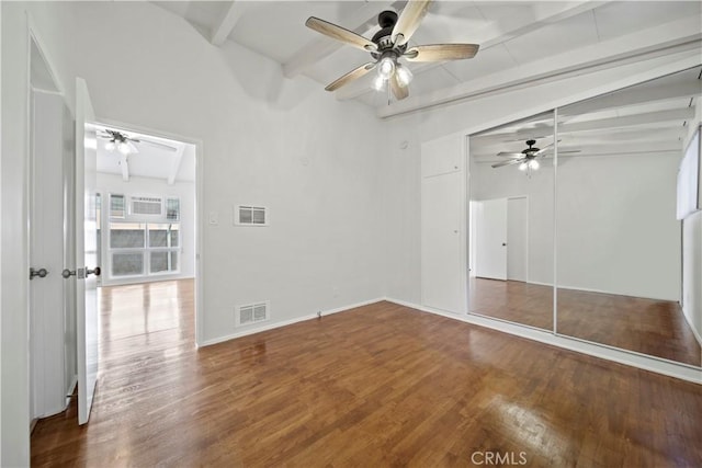 unfurnished bedroom with beamed ceiling, wood finished floors, a closet, a ceiling fan, and baseboards
