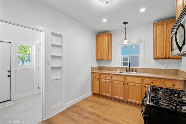 kitchen with a sink, black gas range, ornamental molding, light countertops, and light wood-type flooring