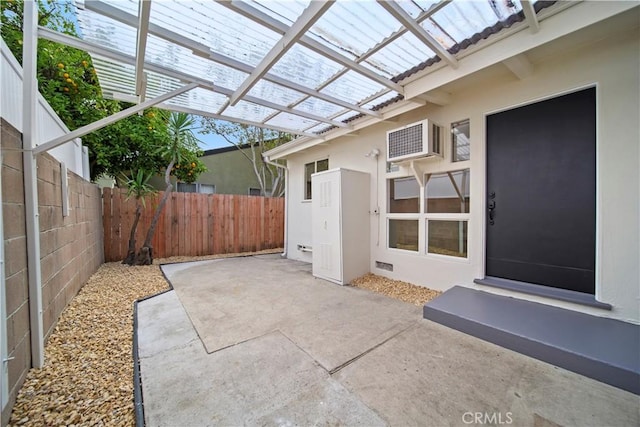 view of patio / terrace featuring a fenced backyard, an AC wall unit, and a pergola