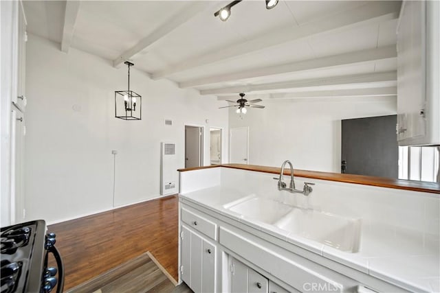 kitchen with a sink, range with gas cooktop, beam ceiling, ceiling fan, and dark wood finished floors