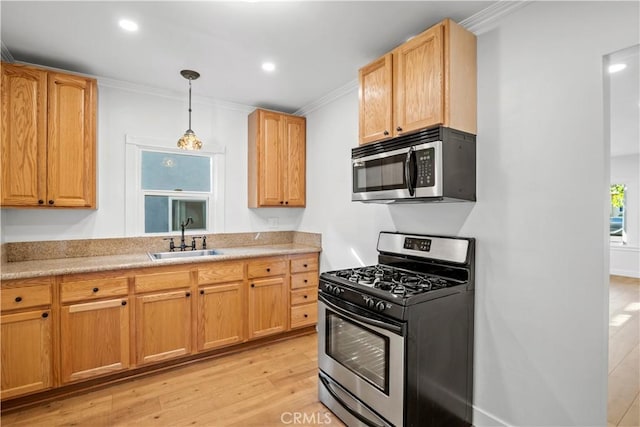 kitchen featuring appliances with stainless steel finishes, a sink, crown molding, light wood-style flooring, and light countertops