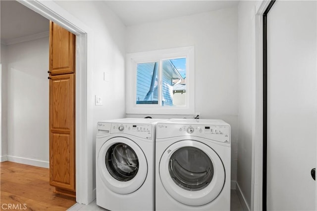 laundry room featuring cabinet space, separate washer and dryer, light wood finished floors, and baseboards