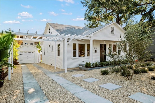 view of front of home with an outdoor structure, a pergola, a detached garage, and driveway
