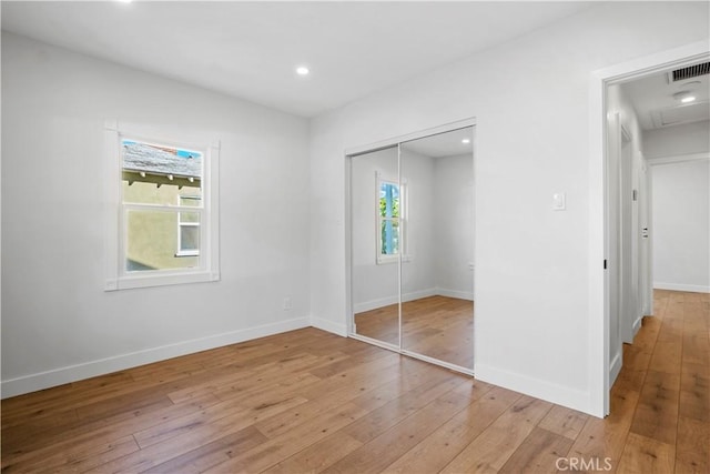 unfurnished bedroom featuring light wood-type flooring, a closet, recessed lighting, and baseboards