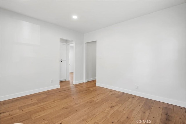 empty room featuring baseboards, light wood-type flooring, and recessed lighting