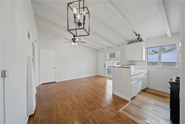 kitchen with black range with gas cooktop, white cabinets, light wood-style flooring, a peninsula, and ceiling fan