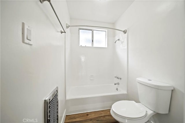 bathroom with toilet, wood finished floors, and tub / shower combination