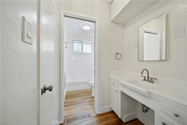 bathroom with toilet, wood finished floors, tub / shower combination, and vanity