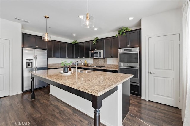 30156 Bristol Gate Ln, Menifee, CA 92584 - kitchen with stainless steel appliances, a sink, dark wood-style floors, pendant lighting, and an island with sink