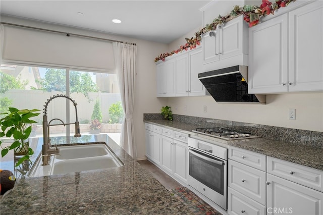 4736 Marrieta St, Jurupa Valley, CA 91752 - kitchen with appliances with stainless steel finishes, a sink, white cabinets, exhaust hood, and dark stone counters