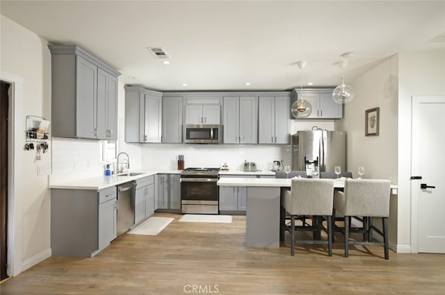 11101 Sarah St, Toluca Lake, CA 91602 - kitchen featuring stainless steel appliances, gray cabinets, a breakfast bar, backsplash, and recessed lighting