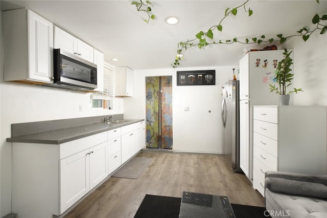 11101 Sarah St, Toluca Lake, CA 91602 - kitchen with appliances with stainless steel finishes, a sink, light wood-type flooring, white cabinetry, and recessed lighting