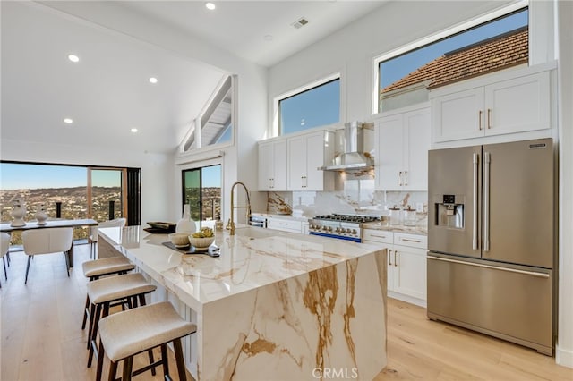 7655 Caminito Avola Ln, Jolla, CA 92037 - kitchen with high end refrigerator, wall chimney range hood, white cabinets, high vaulted ceiling, and light wood-style floors