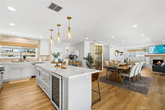 12921 Eveningside Dr, North Tustin, CA 92705 - kitchen with beverage cooler, open floor plan, a sink, white cabinets, and a kitchen bar